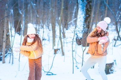 two teenage girls having fun playing with snow, throwing snowballs, having a snow fight. snow games. winter vacation.