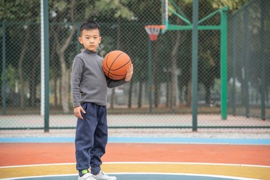 a teenager holding a basketball on the court