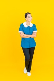 portrait beautiful young asian woman maid and housekeeping smile with action on yellow color background