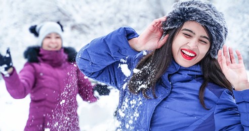 happy friends play snowballs in winter. two cheerful women are having fun time together