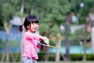 cute asian girl playing badminton. children play sports and exercise. sweet smiling kid are happy. during summer or spring. empty space to enter text. girl age 4 years old wearing pink t shirt.