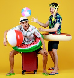 two young asian boys in summer costume laugh as enjoy playing fun outdoor game with ball float, donut tube, and snorkel at swimming pool party as family recreation to relax on vacation of hot season.
