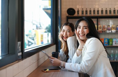 two women smiling joyfully while relaxing in the coffee shop, concept of lifestyle,friend,friendship etc
