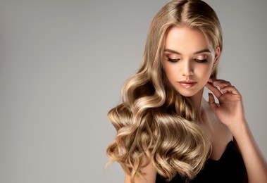 blonde girl with long  and   shiny wavy hair .  beautiful  woman model with curly hairstyle .