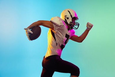 running. power and speed. portrait of male american football player playing, training isolated on blue background in neon light. concept of sport, movement, achievements. copy space for ad