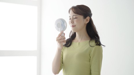 young asian woman using portable fan in summer season