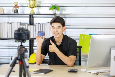 adult asian seller man look intend holding looking at camera to present product via live online for shopping online with e-commerce sell.