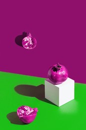 creative composition made of fresh pomegranates on colorful background with white cube and shadows. minimal style. refreshment concept. healthy food ingredient theme.