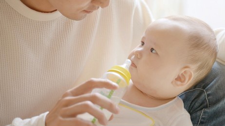 portrait of young father giving milk to baby boy