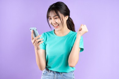 young asian woman using smartphone on purple background
