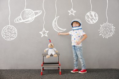 happy child playing with teddy bear at home. kid pretend to be astronaut. imagination and children dream concept