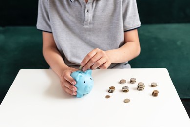 kid teen boy saving money putting coins in a piggy bank. learning financial responsibility and projecting savings. the concept of saving money, finance, business and investment. lessons in mindfulness