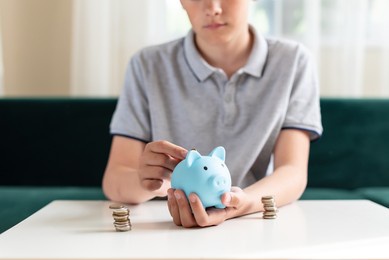 kid teen boy saving money putting coins in a piggy bank. learning financial responsibility and projecting savings. the concept of saving money, finance, business and investment. lessons in mindfulness