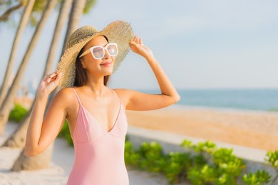 portrait beautiful young asian woman relax leisure around outdoor swimming pool with sea beach ocean view in vacation travel