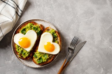healthy holidays breakfast with eggs hearts, croissants and cup of coffee on grey background, top view, copy space