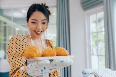 young asian female baking croissant bread preparing breakfast, food and cuisine concept