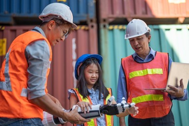 engineer teachers teaching a girl about robot hand in science robotics or engineering class. factory workers check and inspect robotic arm of future biomimetic anthropomorphic robotic technology.
