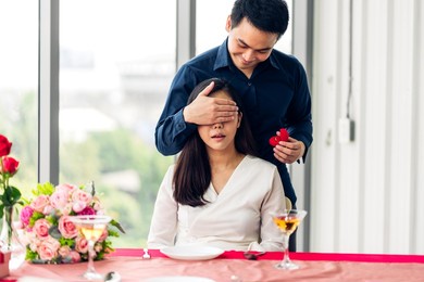 young handsome romantic asian man giving diamond ring for surprise to girlfriend and talking together in valentine day at the restaurant