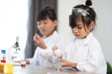 education, science, chemistry and children concept - kids or students with test tube making experiment at school laboratory