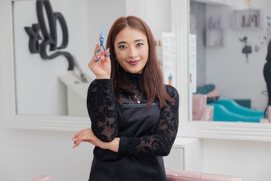 hispanic hairstylist in her beauty salon posing with her scissors. enterprising professional woman in her business - proud professional hairdresser