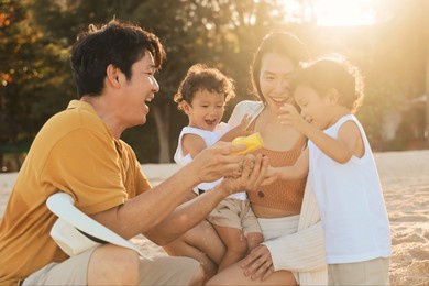 happy asian family on the beach at sunset time, asian twins boy playing with parents on the beach.