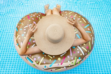 beautiful girl in the in blue swimming pool. pretty teenager in a straw hat with inflatable donut. summer vacation concept. back view. summer vacation concept. teenager stock photo