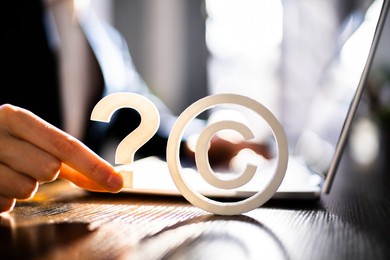 copyright sign near man's hand working on laptop