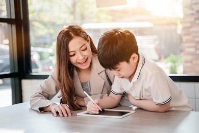 businses woman working online in cafe with kid. asian family lifestyle with mobile phone and digital tablet.