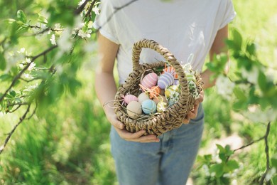 easter egg hunt in spring garden. funny teen girl with eggs basket and bunny ears on easter egg hunt in sunny spring garden. celebrating easter. happy easter card