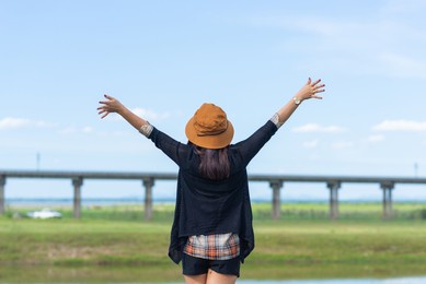 back side of happy woman freedom lifestyle traveler in thailand vacation journey at the dam with sky.