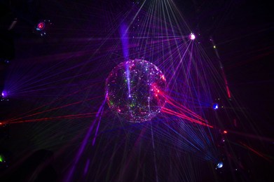 mirrored disco ball and bright beams at the night party. party attribute reflects lazer lights. abstract background with defocused rays. night club atmosphere. installation at vilnius light festival