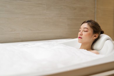 young woman relaxing in bathtube with eyes closed in bathroom