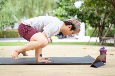 active sportsman doing a plank - yoga exercise and making a video call with a friend and online sport training coach online. healthy sport man making a body building workout with online instructor.