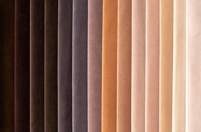 fabric swatches in different colors are stacked for selection. a variety of shades of upholstery material for furniture and interior. fabric texture close up. a set of multi-colored rolls of material.