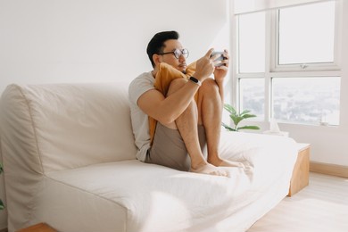 adult asian man is having fun to play mobile game in the living room apartment.