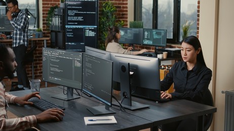 two focused coders facing each other writing code in software development office while team of coders are developing artificial intelligence. team of programmers innovating algorithm code.