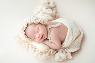 happy adorable cute asian newborn baby wrapped in cocoon with  sleeping on bed
