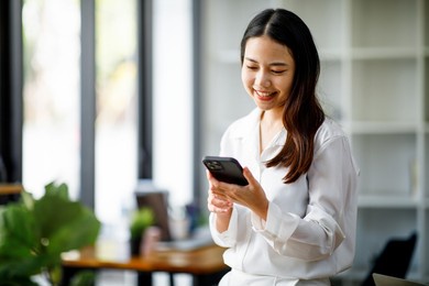 portrait of a happy asian businesswoman using mobile phone indoor, asian businesswoman working in modern office.