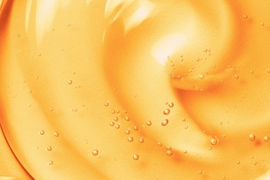 orange gel texture background. gold cosmetic transparent cream swirl with bubbles. citrus fruit skincare product closeup