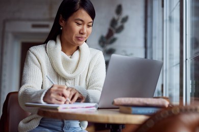 an asian female student sitting in cafeteria and studies for a test.
