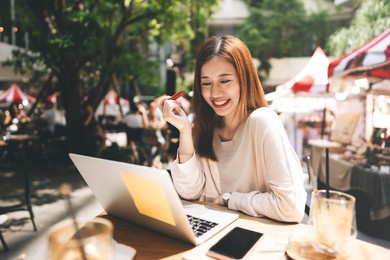 business freelancer adult asian woman using laptop computer for work at sidewalk cafe. happy and smile face. urban people lifestyle with modern technology on day.