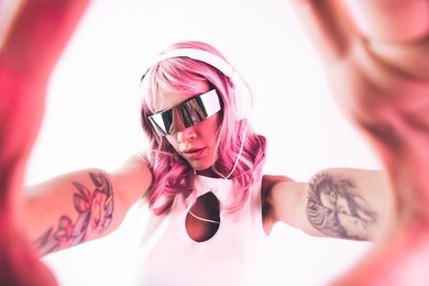 young woman with pink hair dancing and having fun. colored gel portraits with futuristic outfit