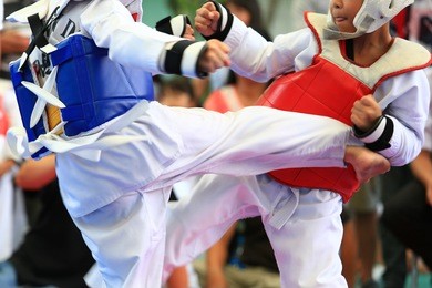 young taekwondo athletes are fighting during contest