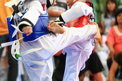 young taekwondo athletes are fighting during contest