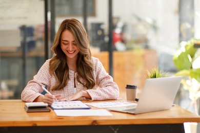 portrait of asian businesswoman with laptop writes on a document at the coffee shop, asian woman  doing planning analyzing the financial report, business plan investment, finance analysis concept
