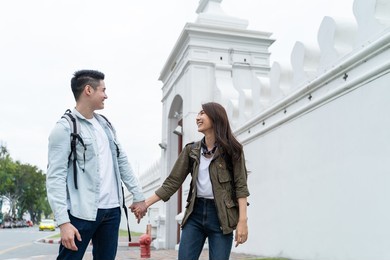 asian attractive romantic couple travel in the city for honeymoon trip. young new marriage man and woman backpacker tourist holding hand each other and enjoy spend time on holiday vacation together.