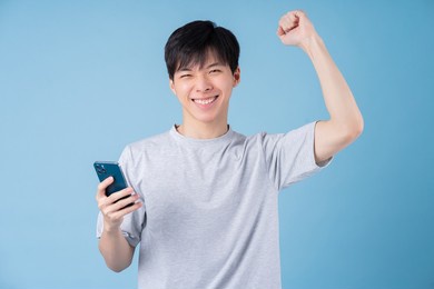 young asian man using smartphone on blue background