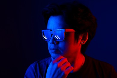 asian man wearing fashion sunglasses in dark blue and red light with copy space