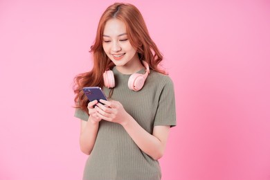 young asian woman using smartphone on pink background