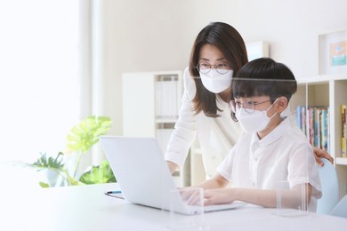 smart young student is learning while talking online while being tutored by her mother and teacher in a remote class on a laptop.
